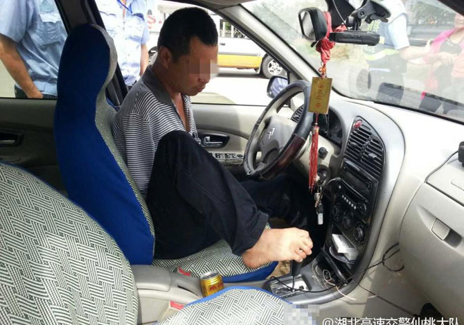 両腕がなく両足で運転する男性