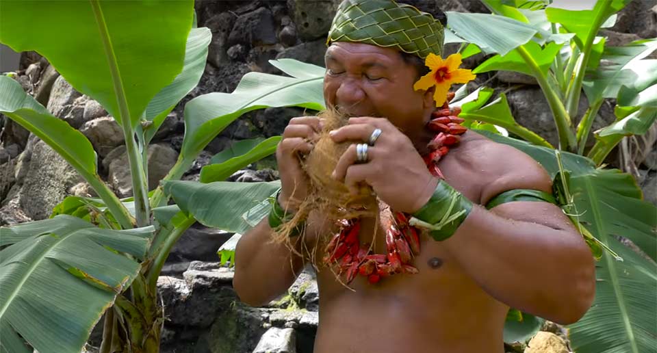 ココナツの殻の剥き方をレクチャーするポリネシアの男